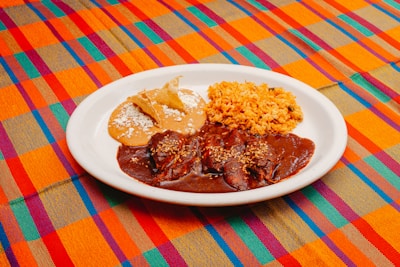 A white plate topped with meat and rice
