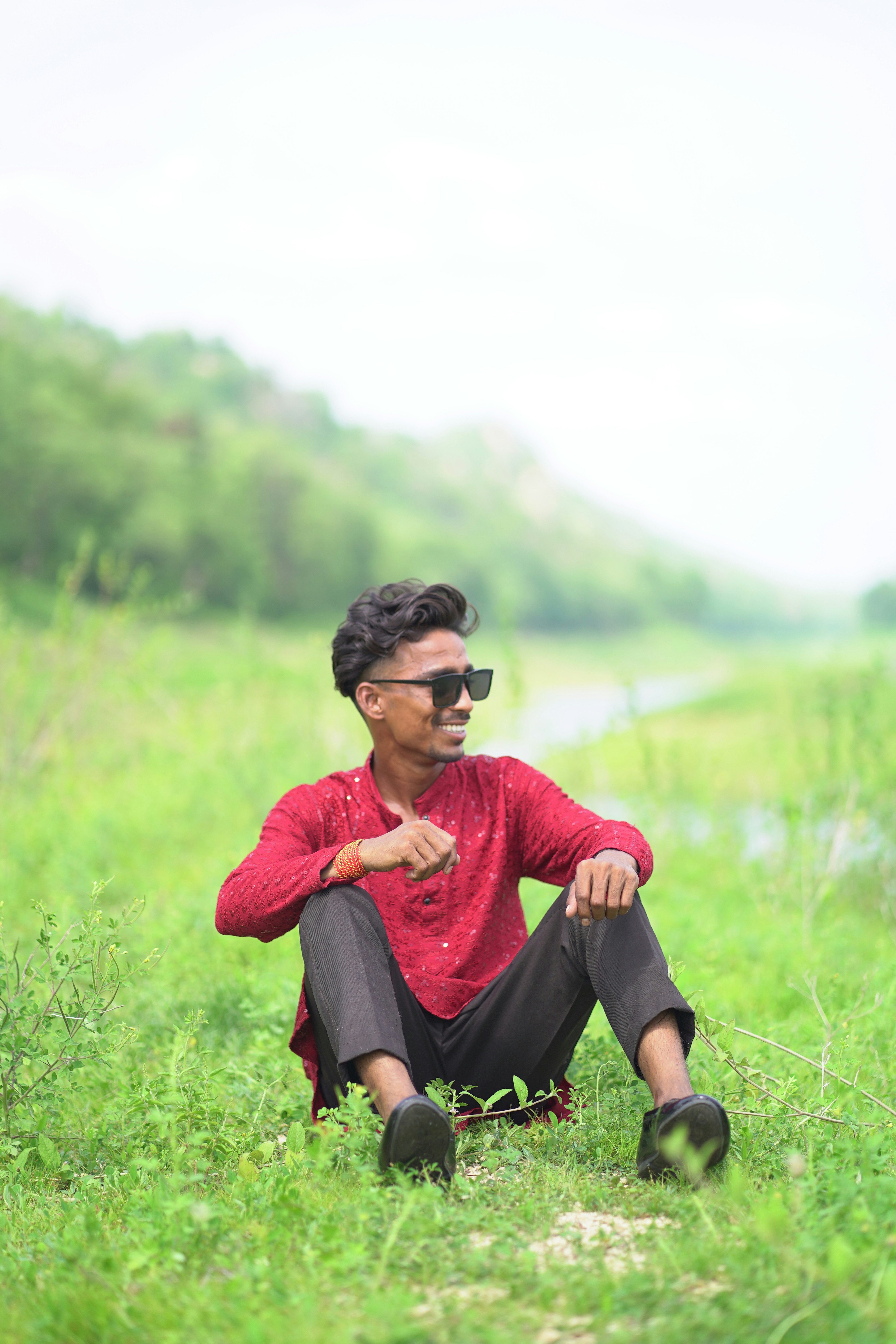 A man in a red shirt is sitting in a field