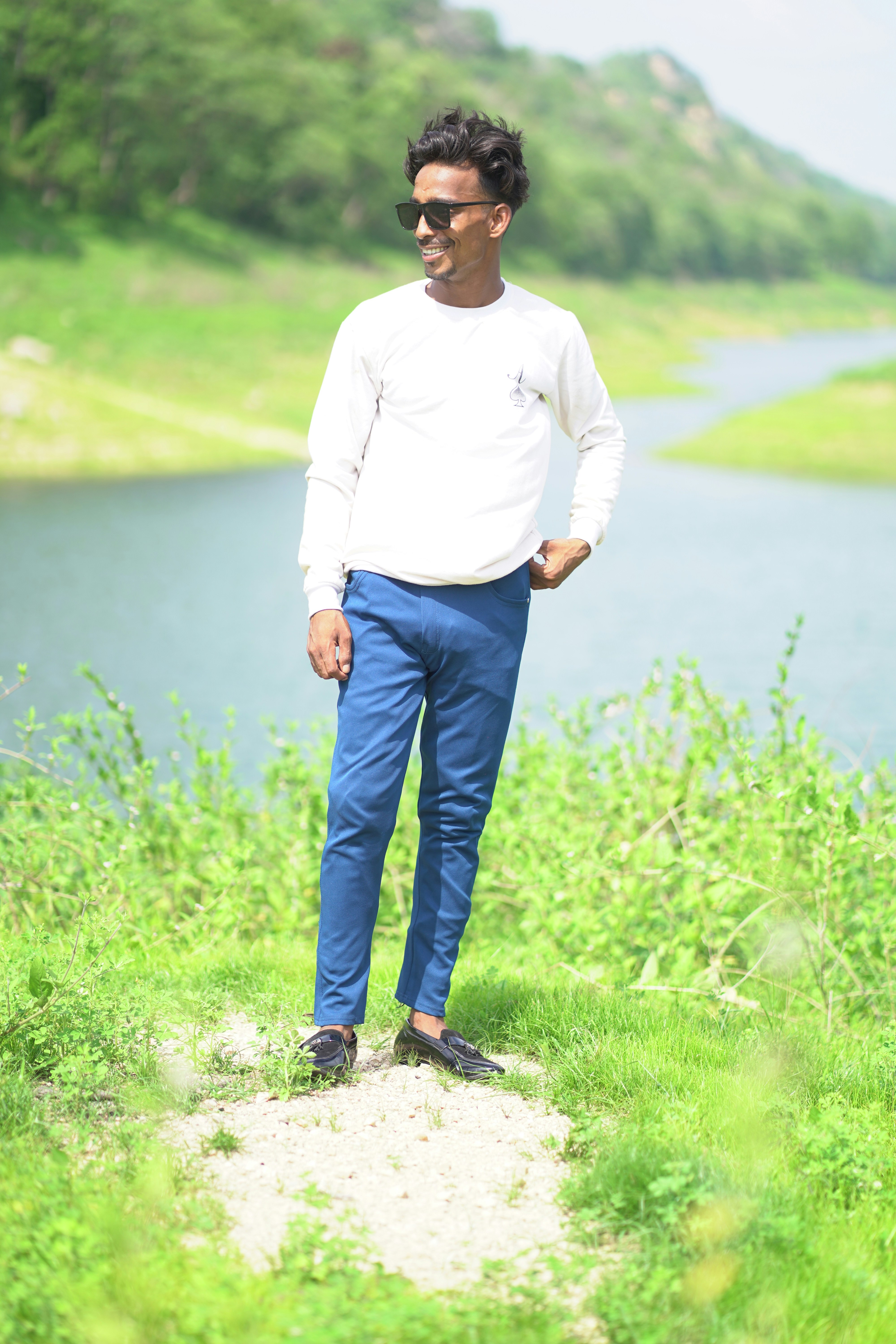 A man standing in a field next to a body of water