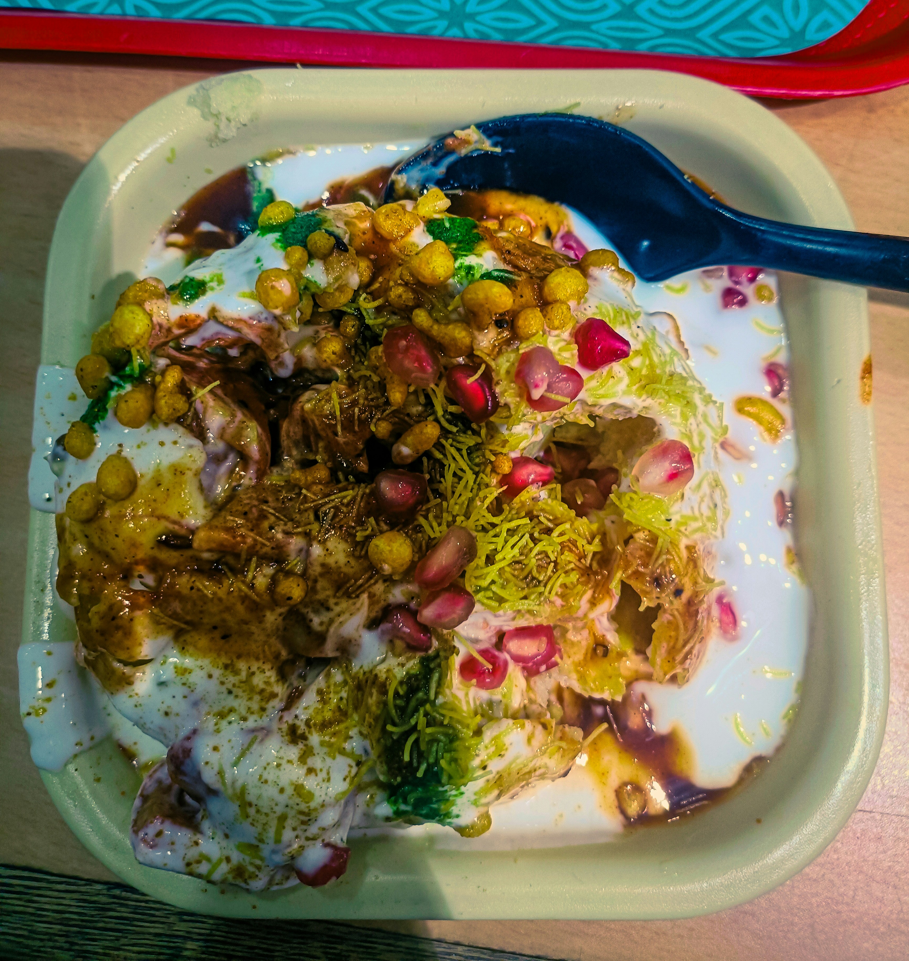 Samosa chaat plate with yogurt chutneys and pomegranate seeds, white plate