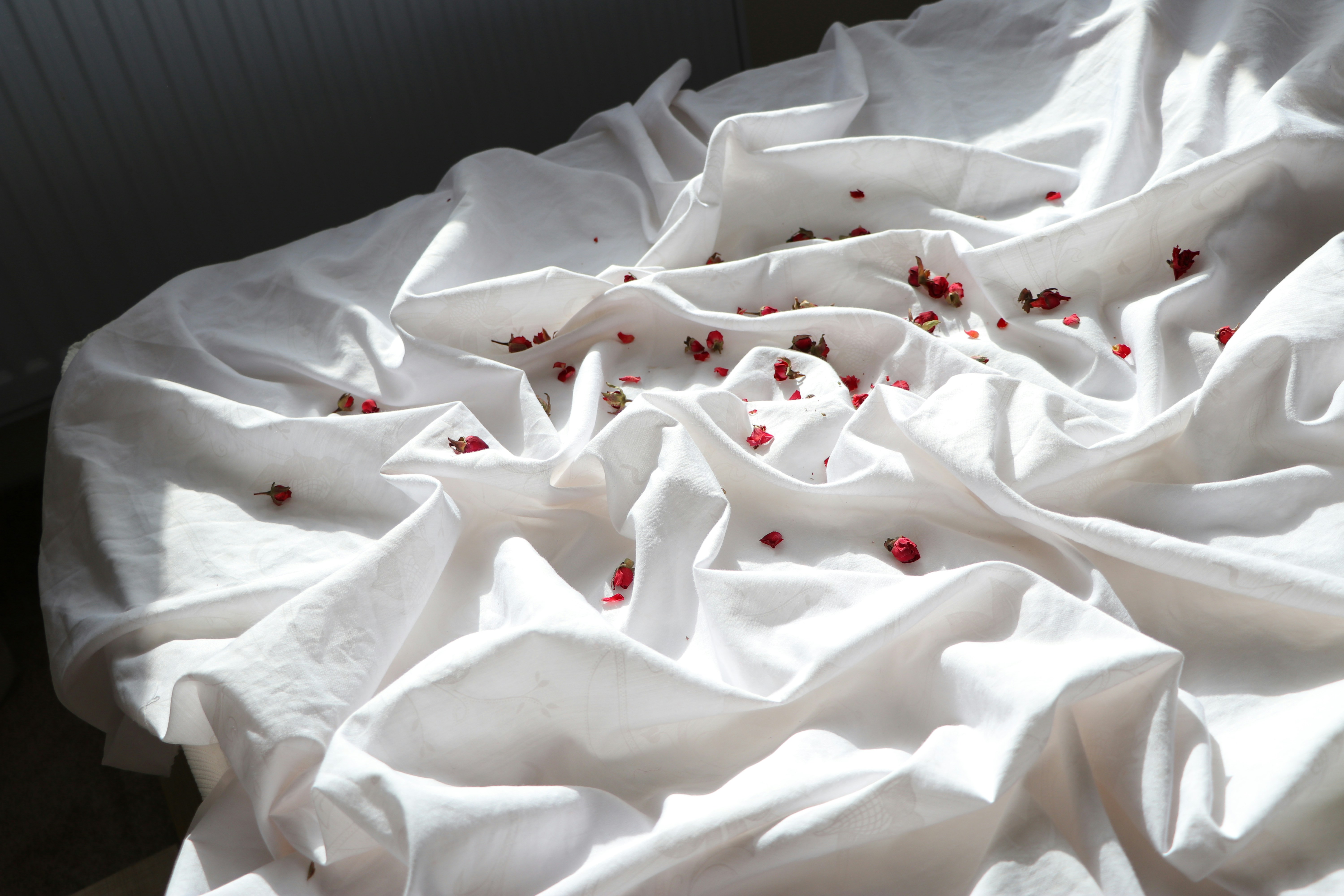 A bed with white sheets and red sprinkles on it