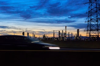 A car driving past a power plant at dusk