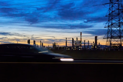 A car driving past a power plant at dusk