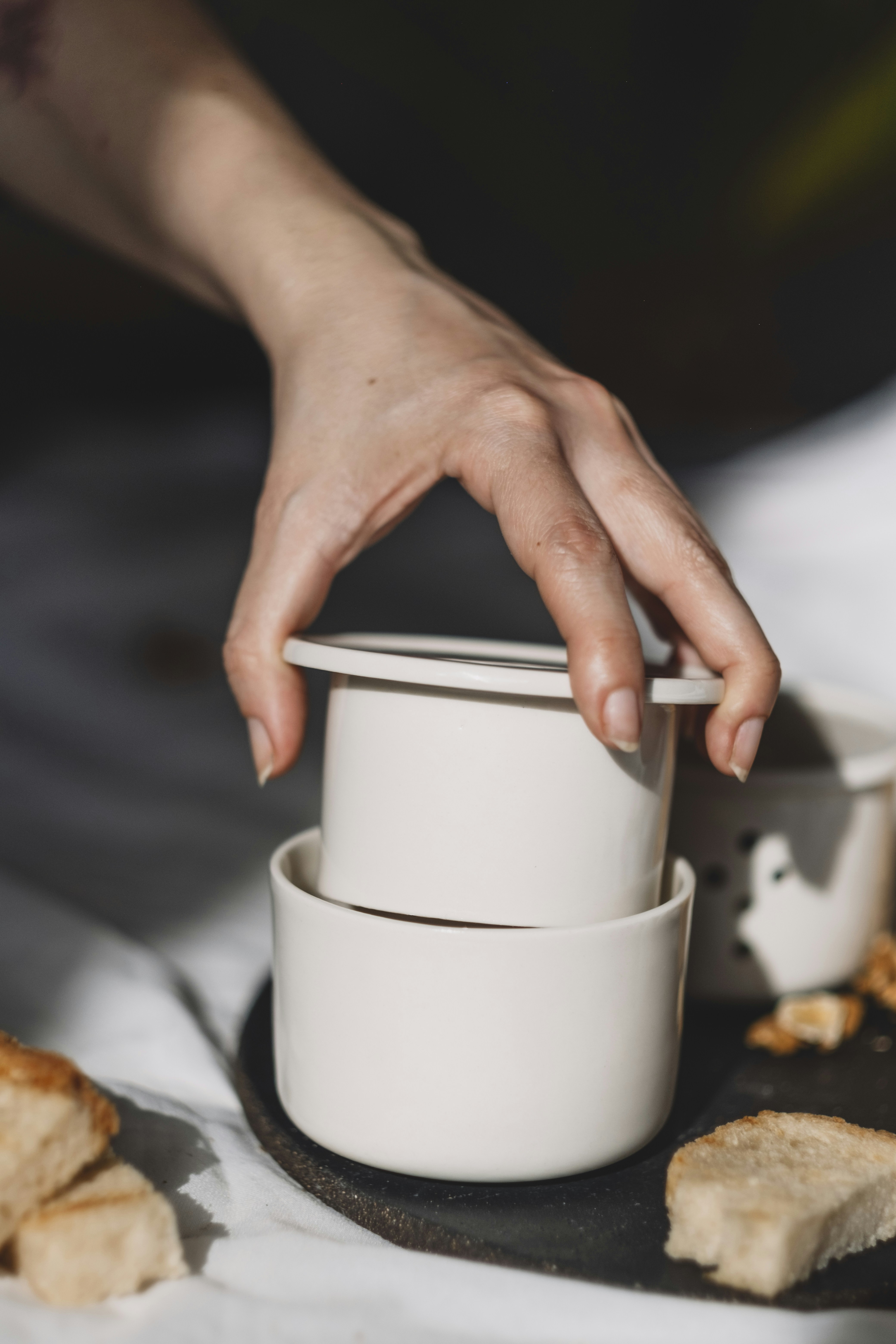 A person reaching for a piece of bread on a plate