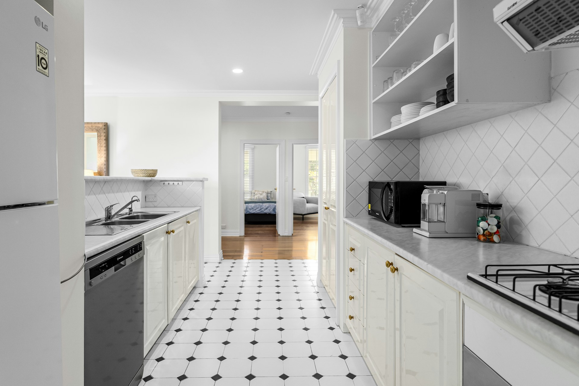 A kitchen with white cabinets and a black and white floor