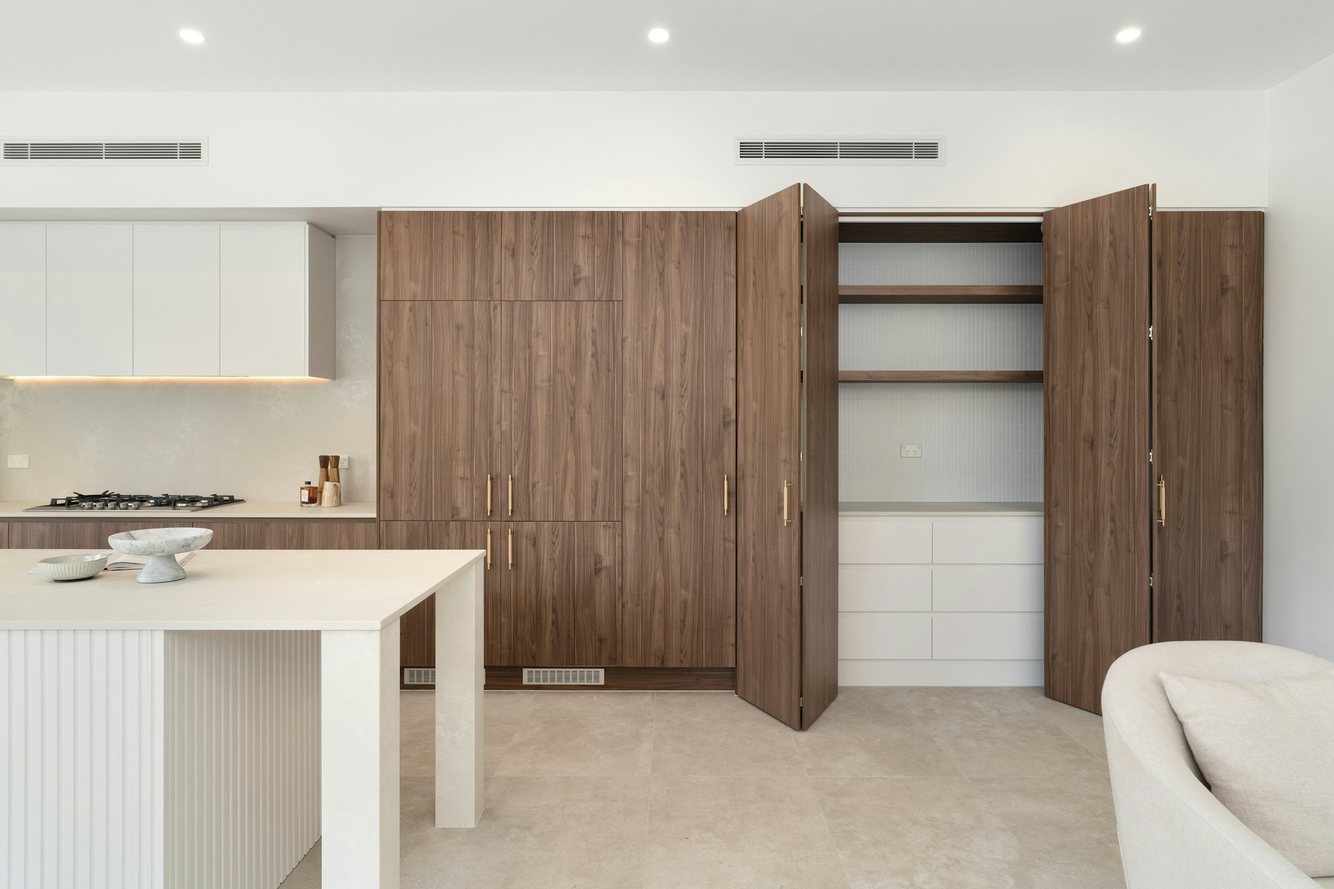 A kitchen with a white counter top next to a white couch