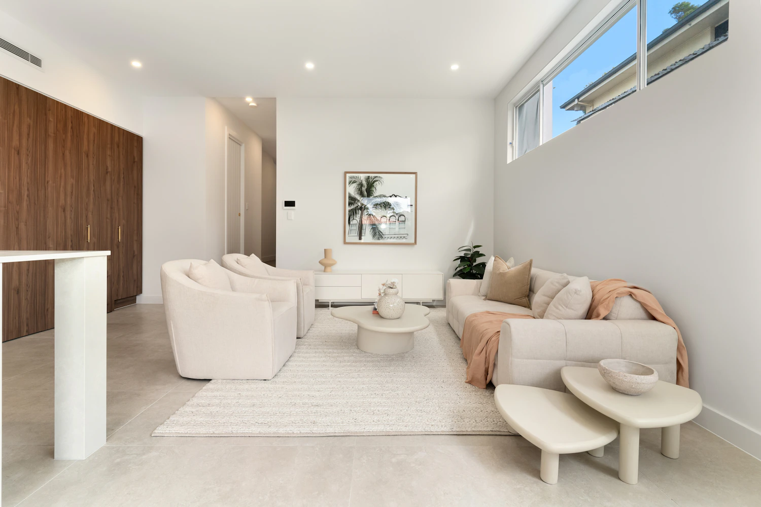 A sunlit living room with a soft sofa and sculptural coffee tables
