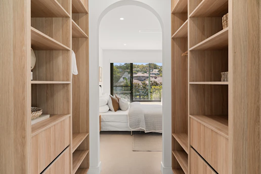 A walk in closet with a bed and a window