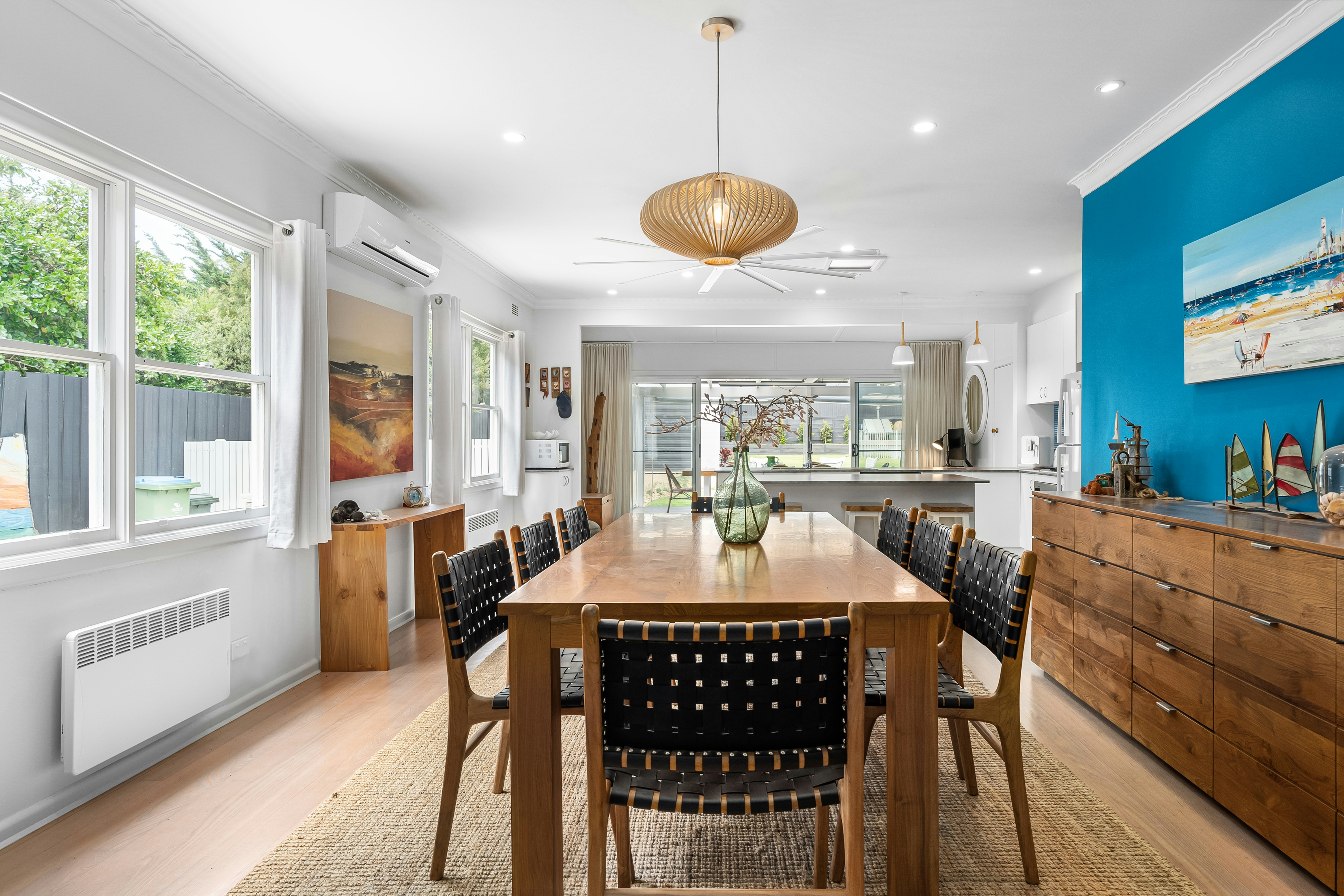 A dining room with a large wooden table surrounded by black chairs