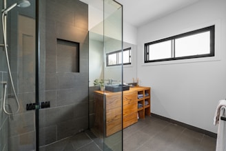 A bathroom with a walk in shower next to a sink