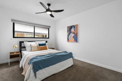 A bedroom with a bed and a ceiling fan