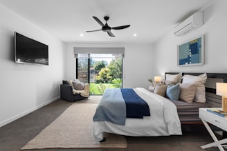 A bed room with a neatly made bed and a flat screen TV