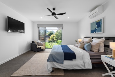 A bed room with a neatly made bed and a flat screen TV