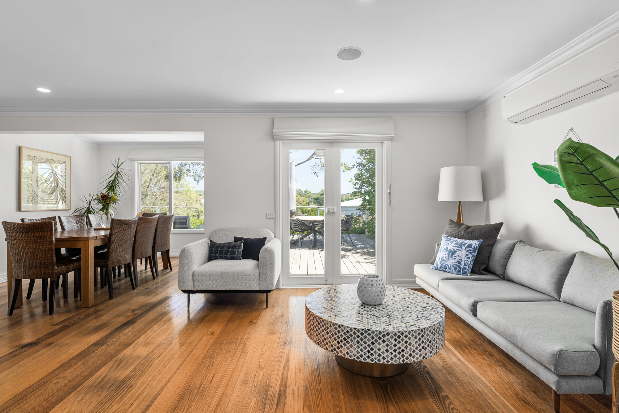 Warm wood floor beneath sculptural furniture in a light-filled living room