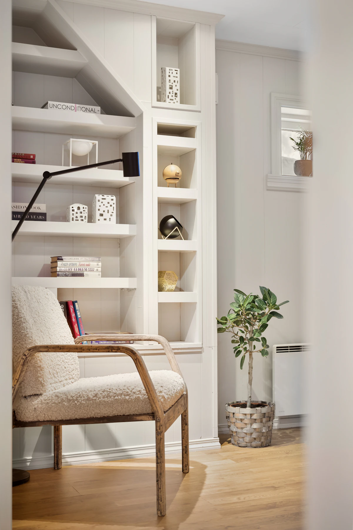 Potted plant beside a reading chair and bookshelf