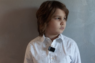 A young boy wearing a white shirt and black tie