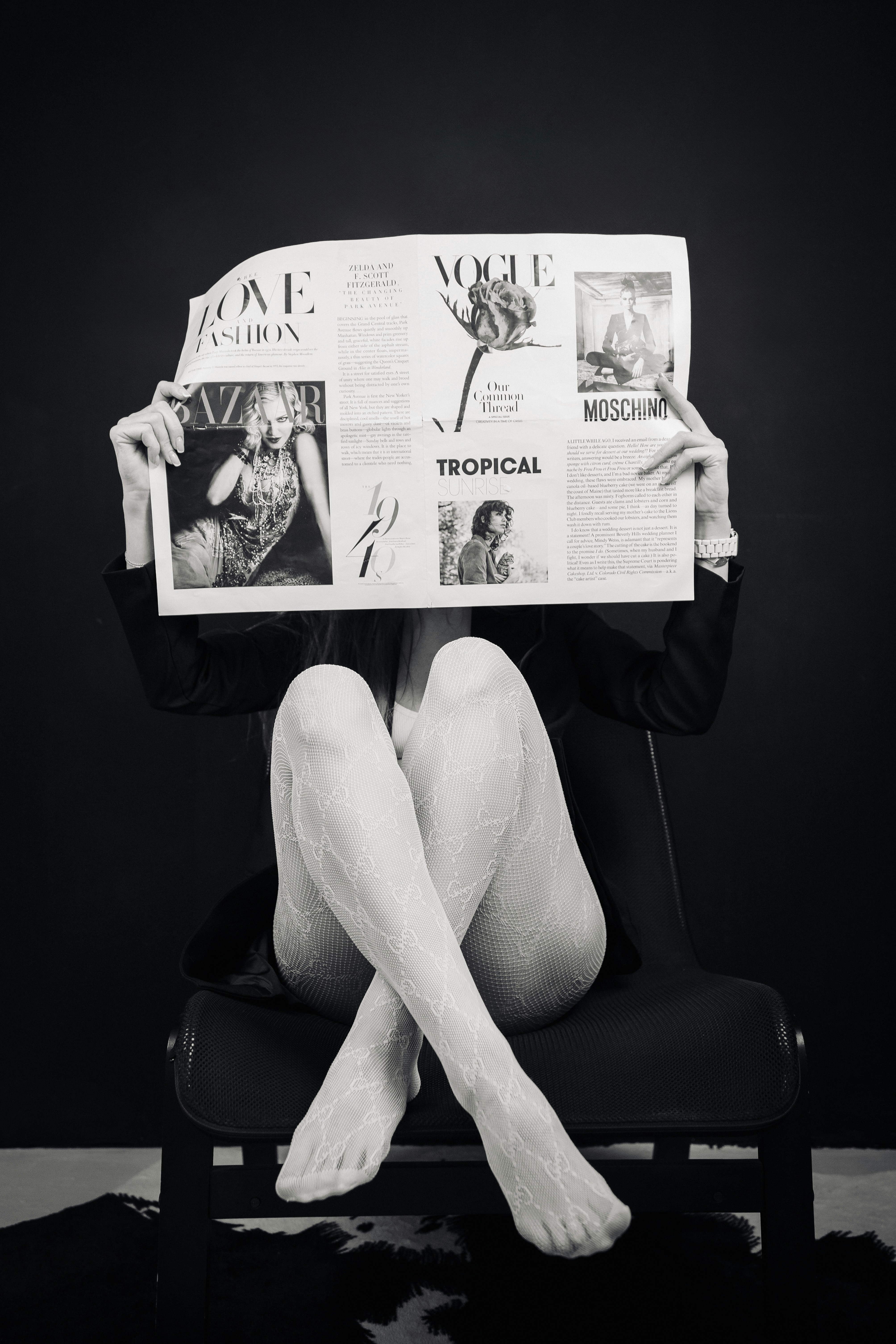 A woman sitting on a chair holding up a newspaper