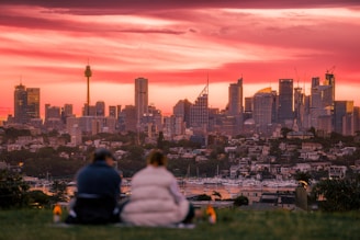 A man and a woman sitting on a hill overlooking a city