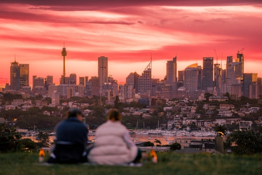 A man and a woman sitting on a hill overlooking a city