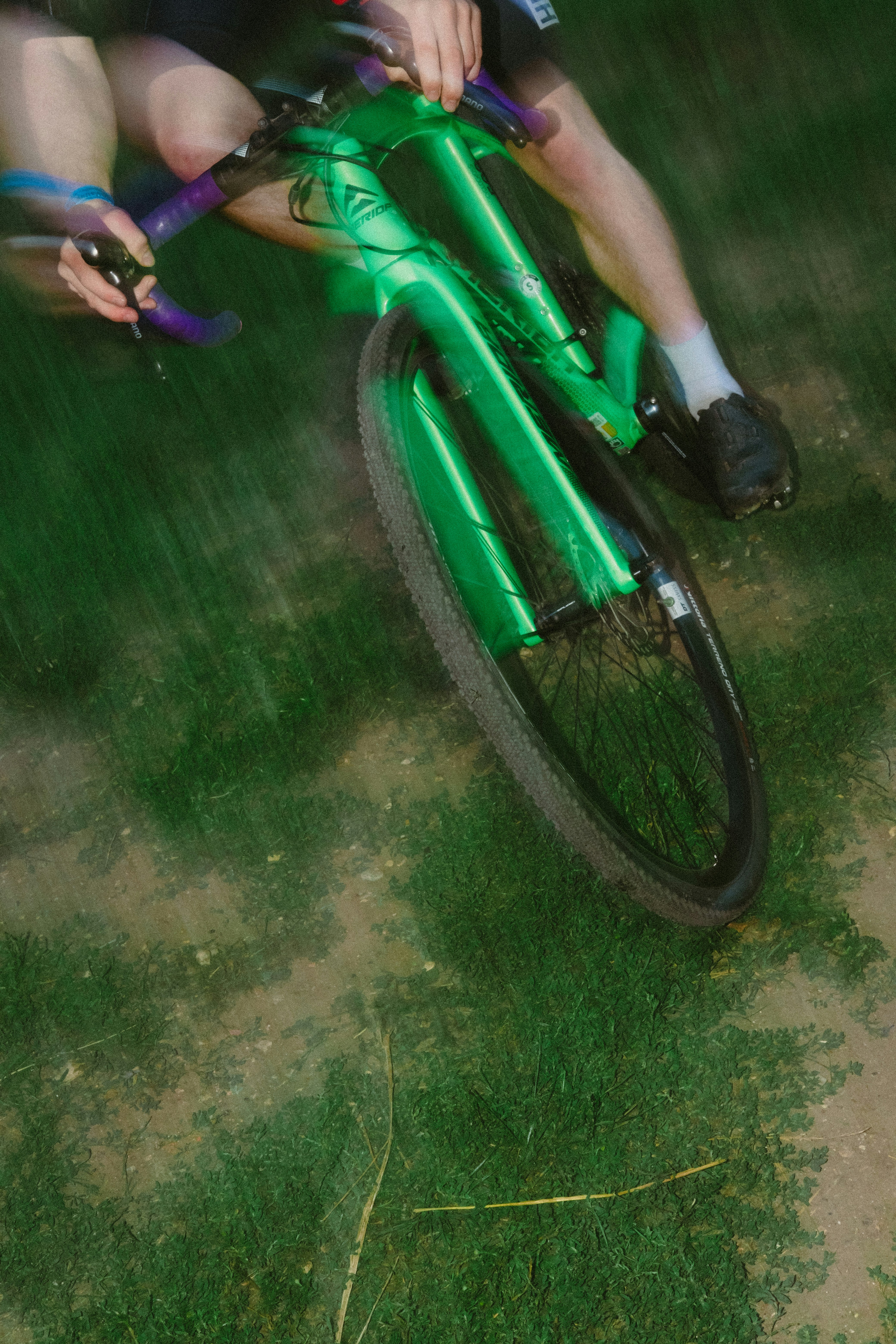A man riding a green bike on top of a lush green field
