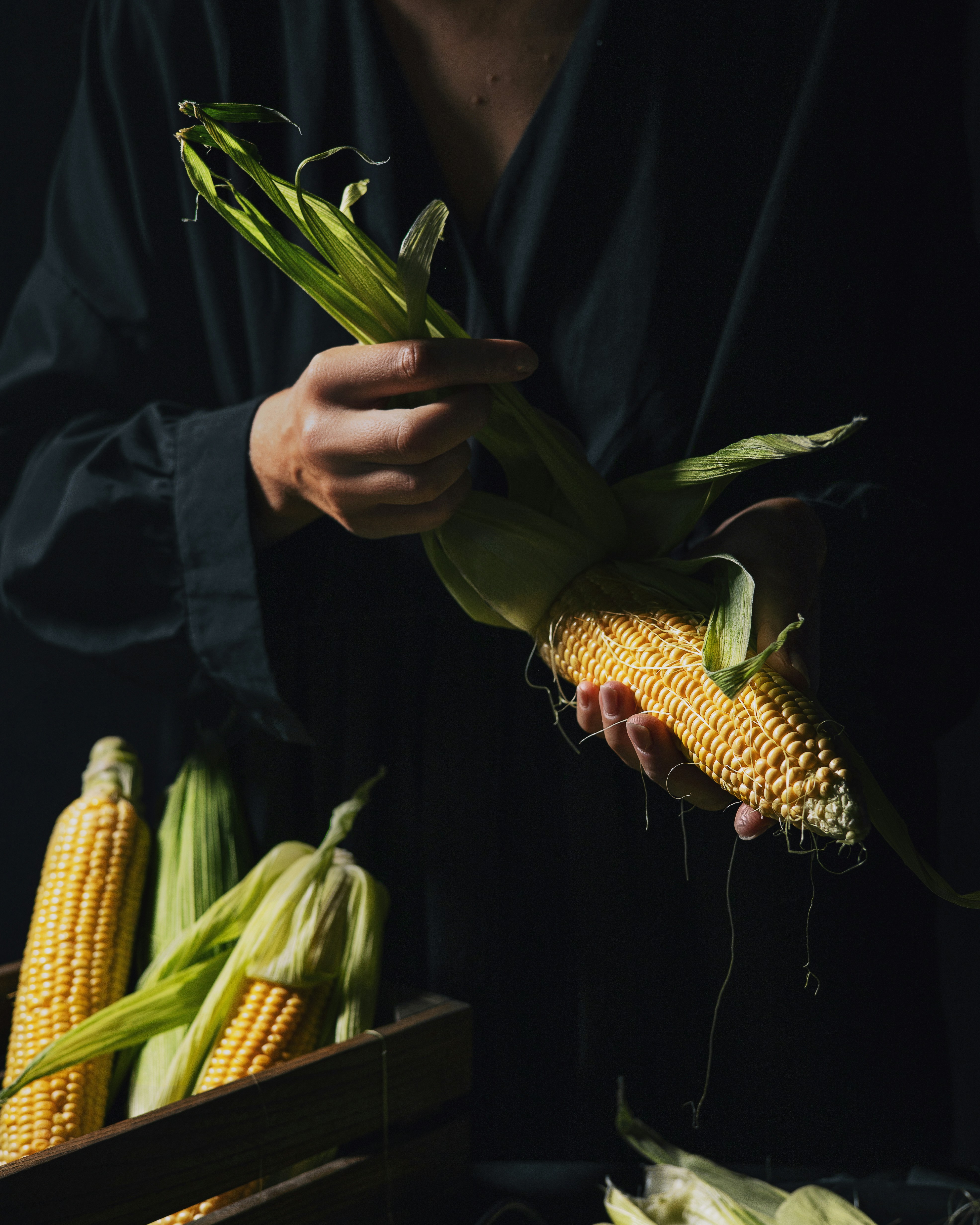 A woman holding a stalk of corn in her hands