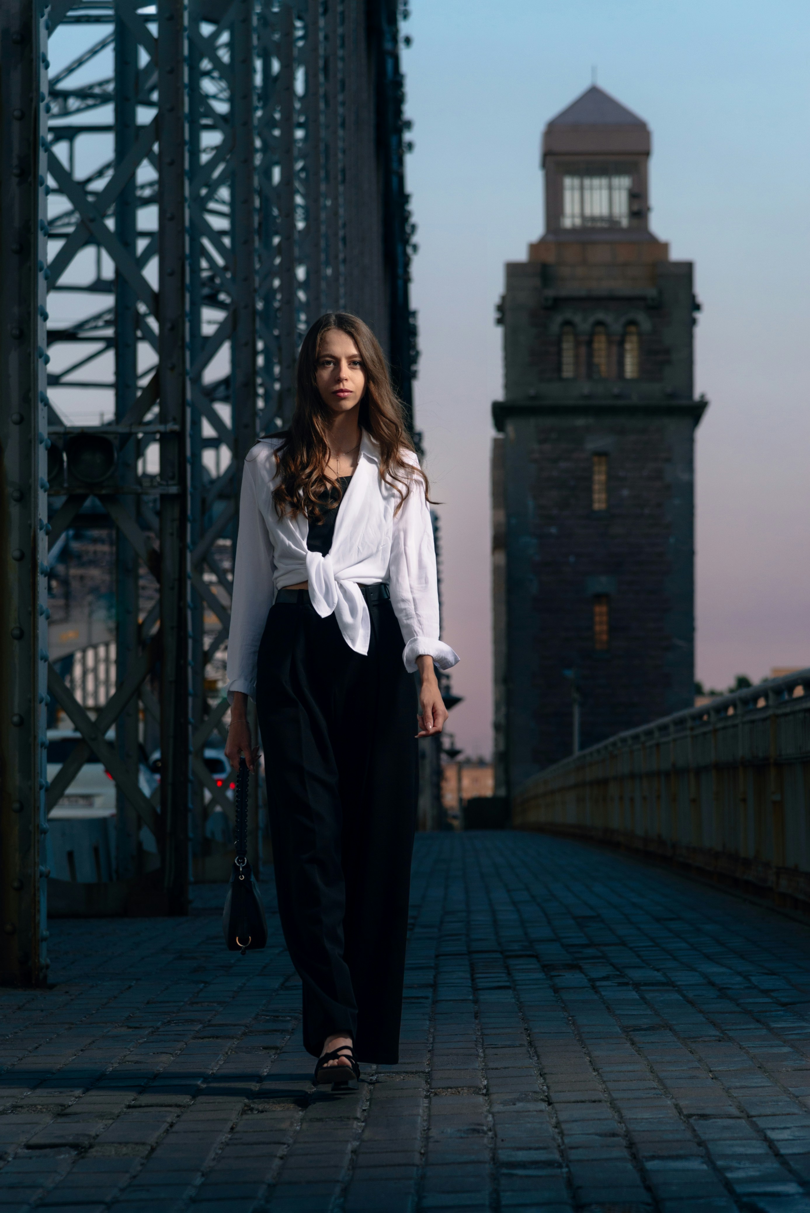 Una donna che cammina su un ponte con una torre dell'orologio sullo sfondo