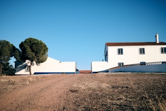 A white house sitting on the side of a dirt road