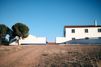 A white house sitting on the side of a dirt road