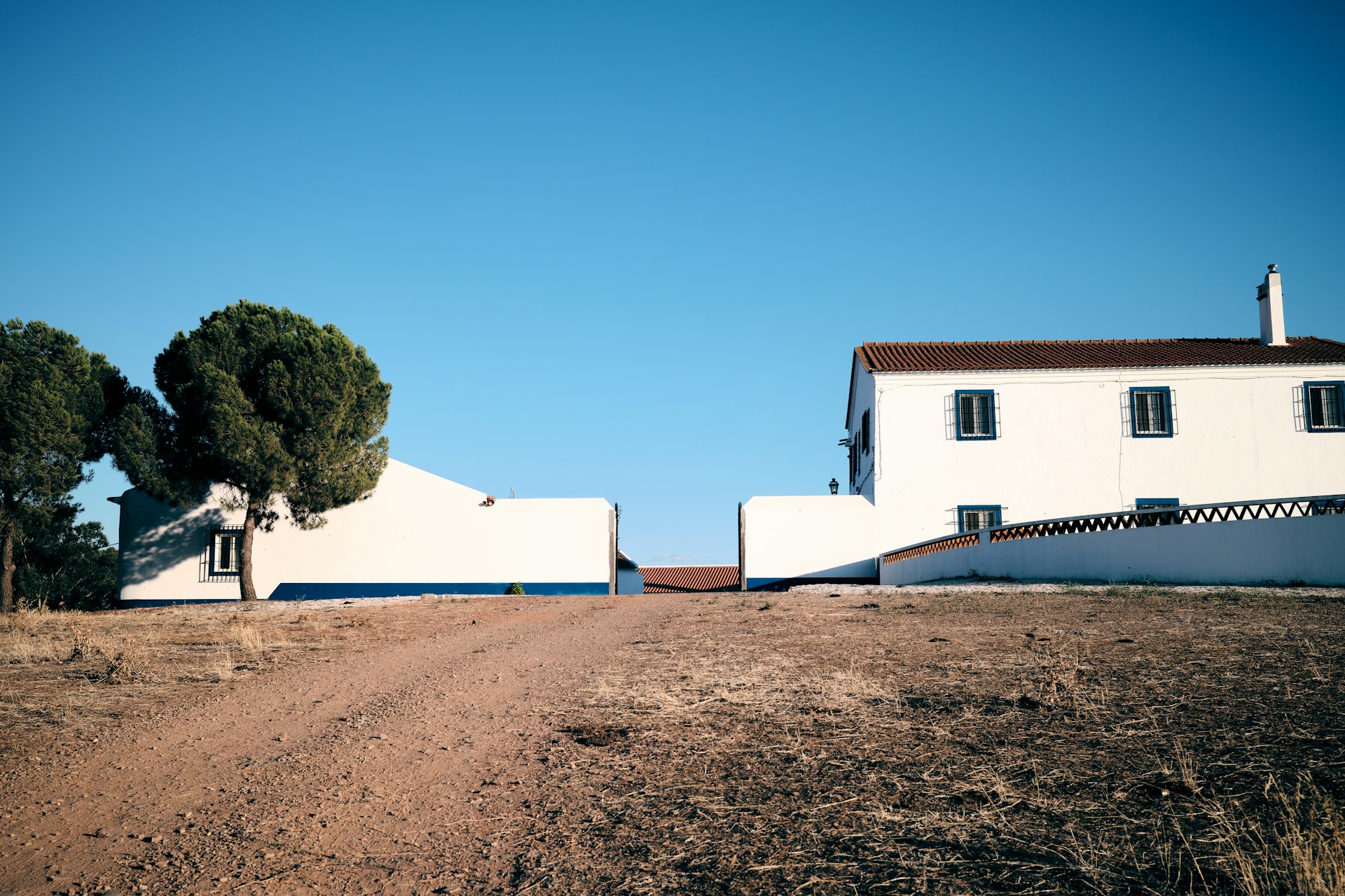 A white house sitting on the side of a dirt road