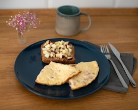 A blue plate topped with food next to a cup of coffee