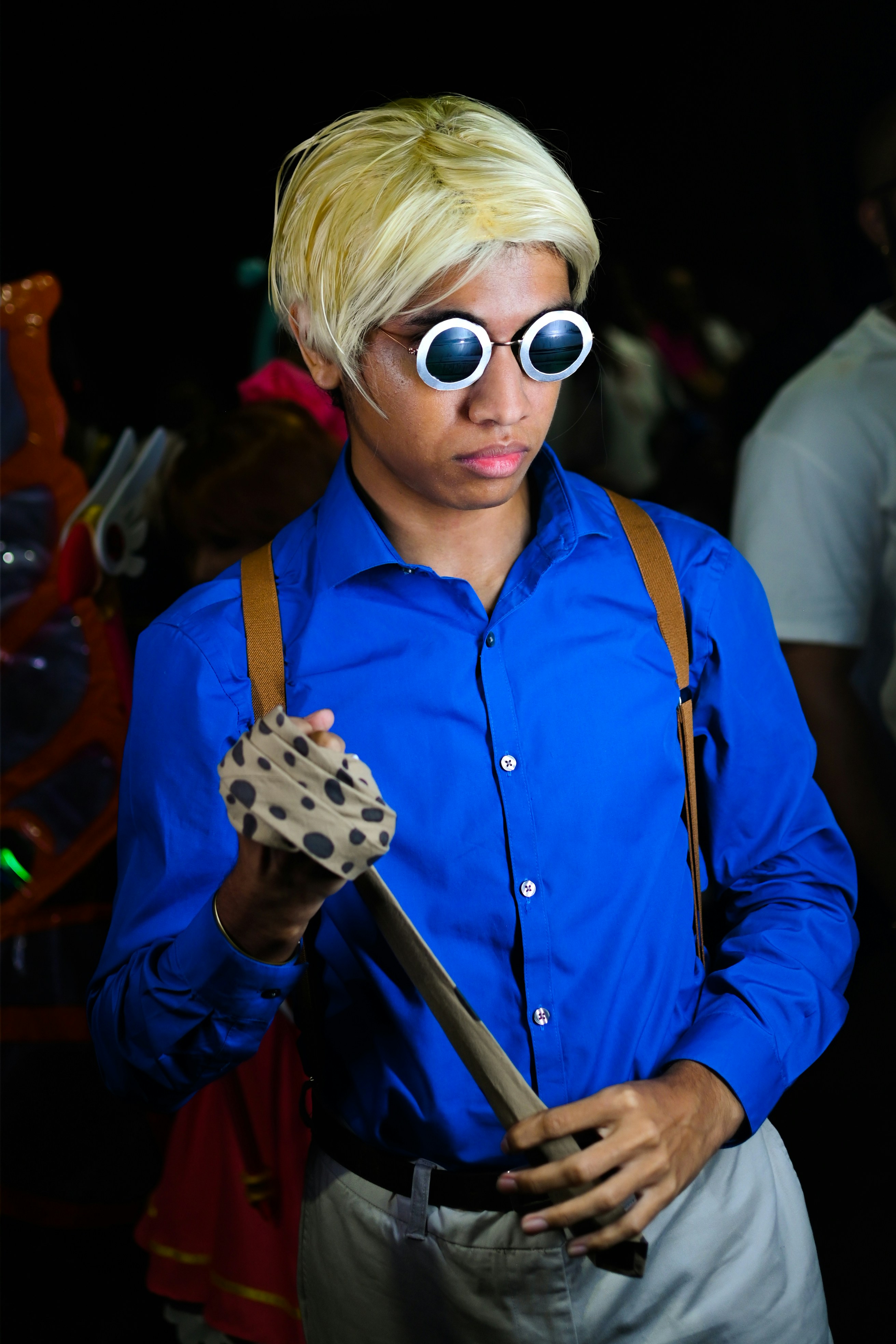 Seorang pria dengan kemeja biru dan suspender memegang gitar