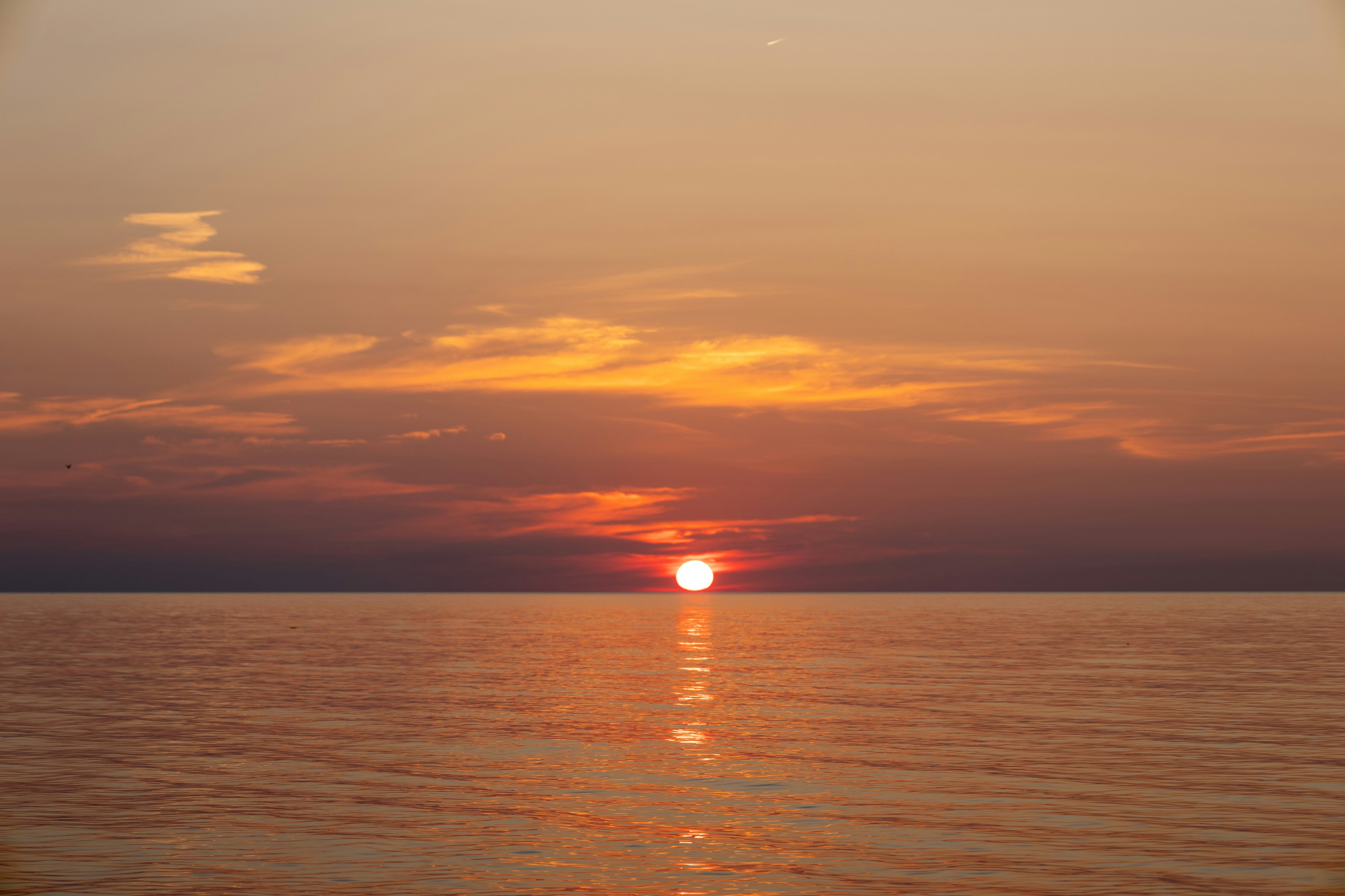 The sun is setting over the ocean on a cloudy day