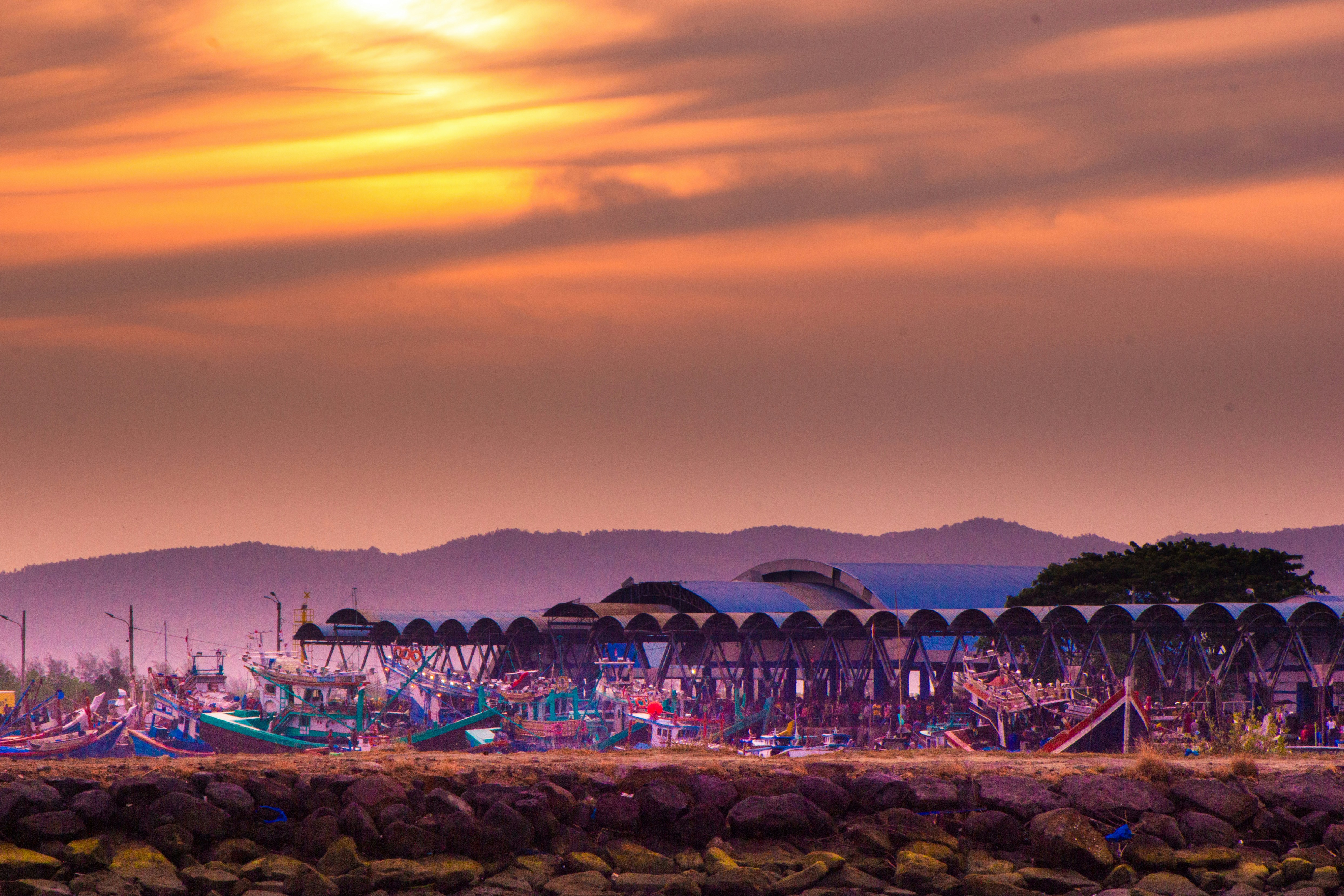 A sunset view of a beach with a pier and mountains in the background