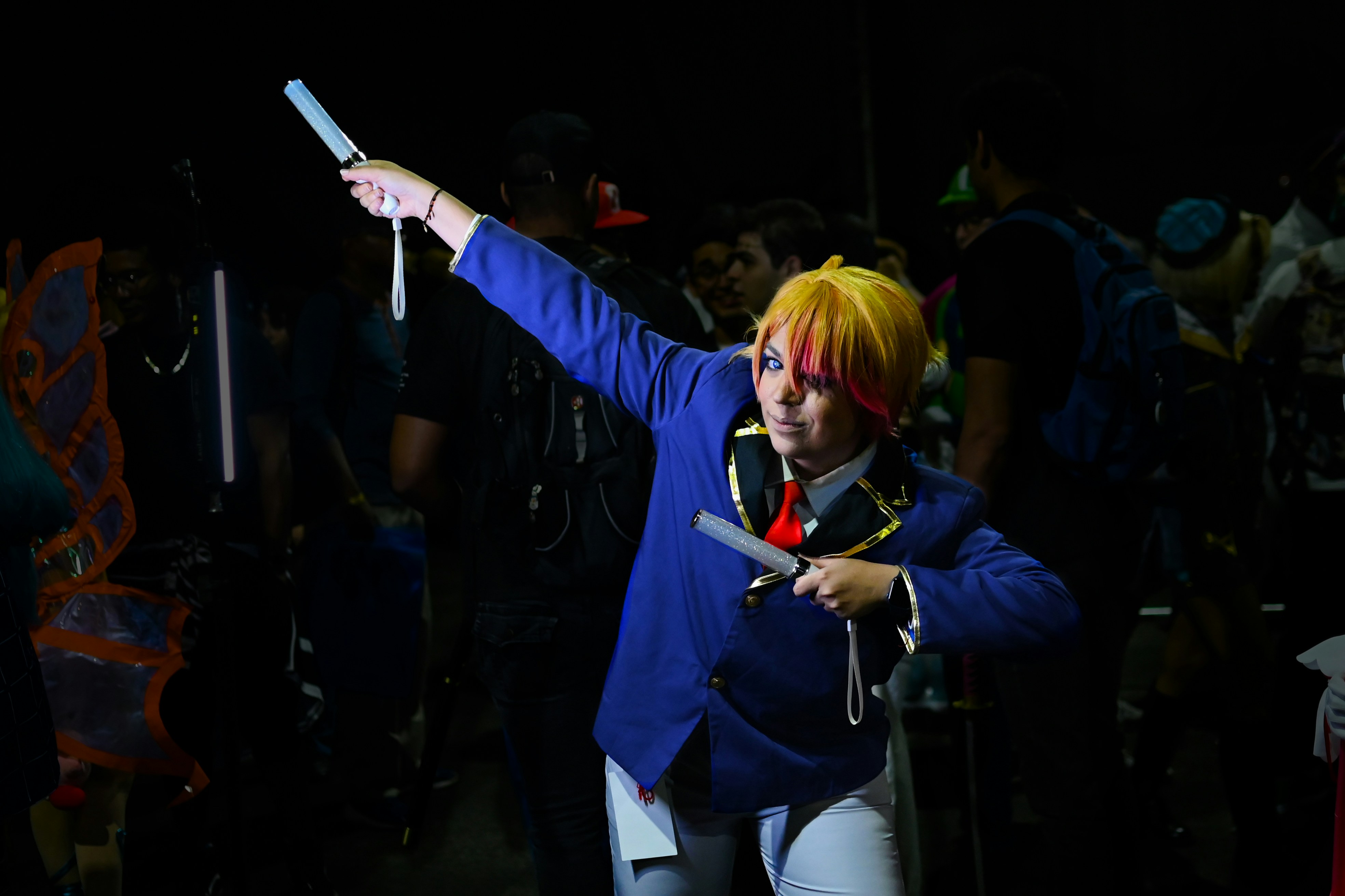 Seorang pria berjaket biru memegang pengontrol game nintendo wii