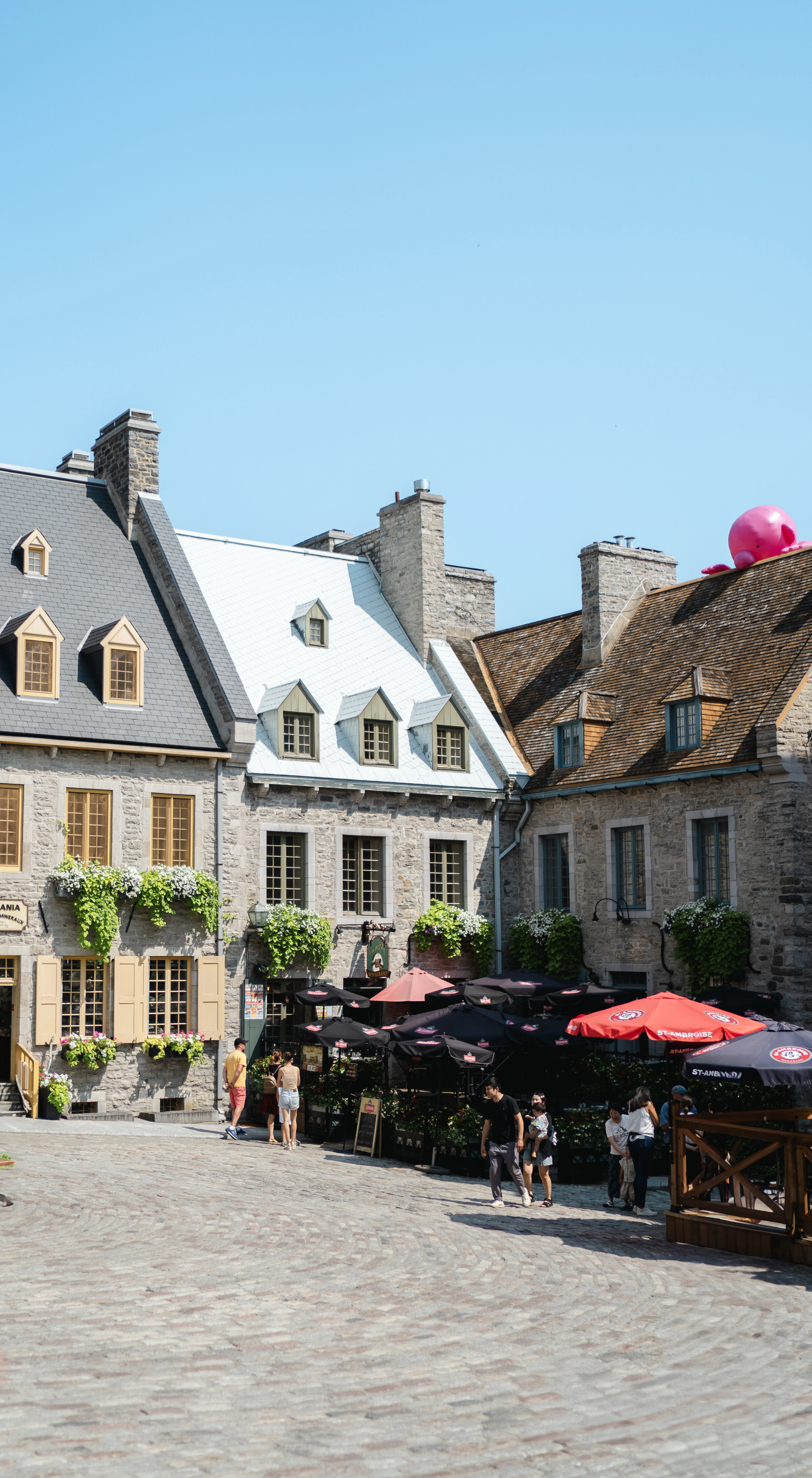 Stone houses with mansard roofs and cafe umbrellas around the cobbled Place Royale in Old Quebec's Lower Town