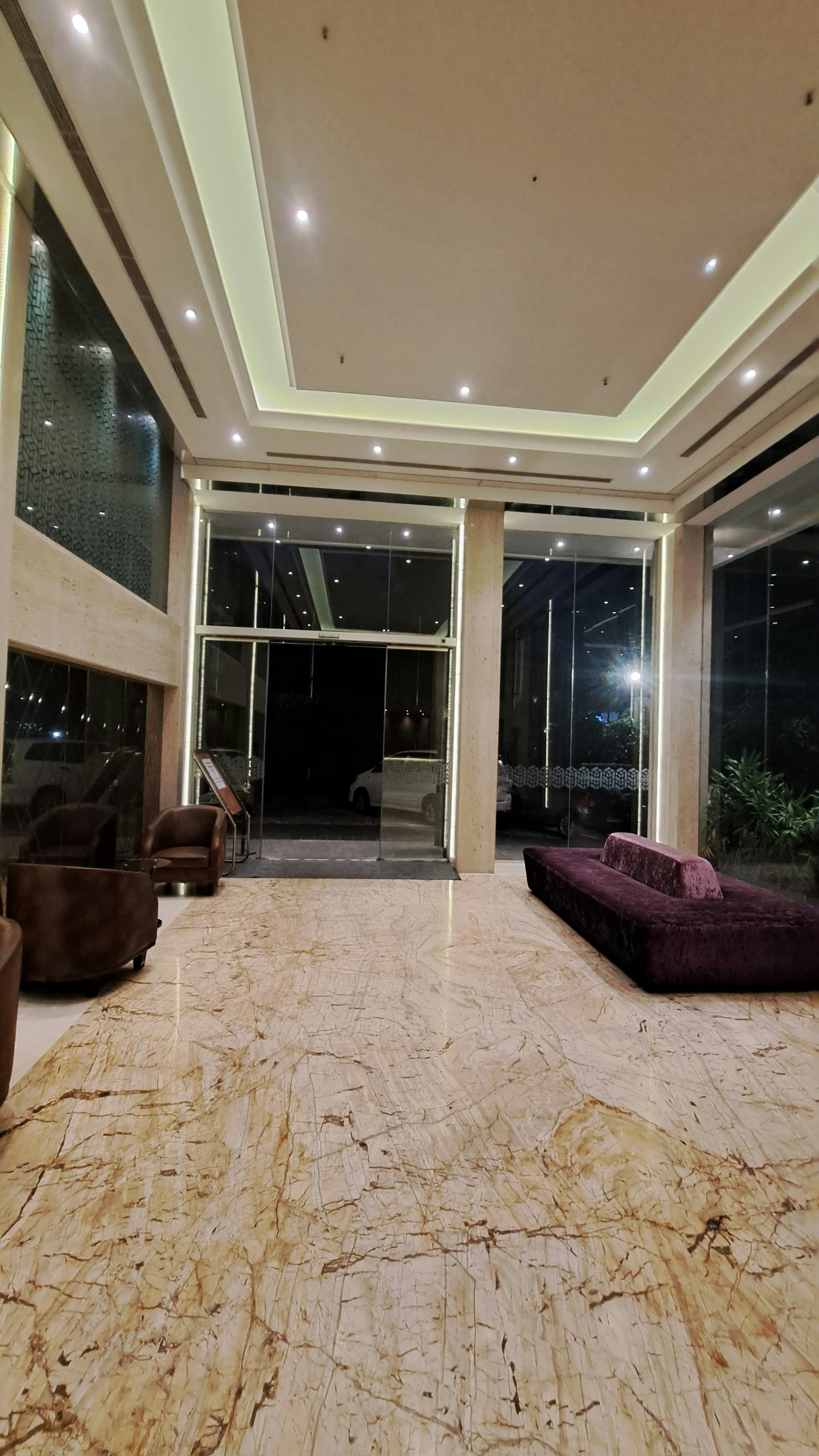 Elegant hotel lobby with warm lighting, marble floors, and luxurious seating in bright open space