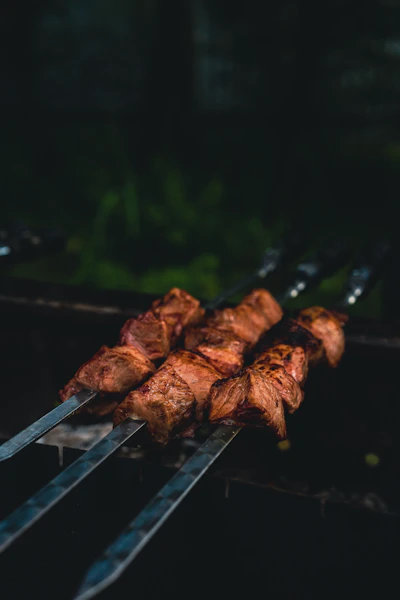 A close up of meat on a grill with tongs