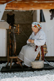 A woman sitting on a chair next to a spinning wheel