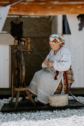A woman sitting on a chair next to a spinning wheel