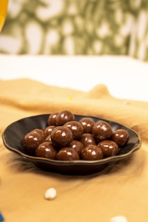 A plate of chocolates on a bed with a glass of wine