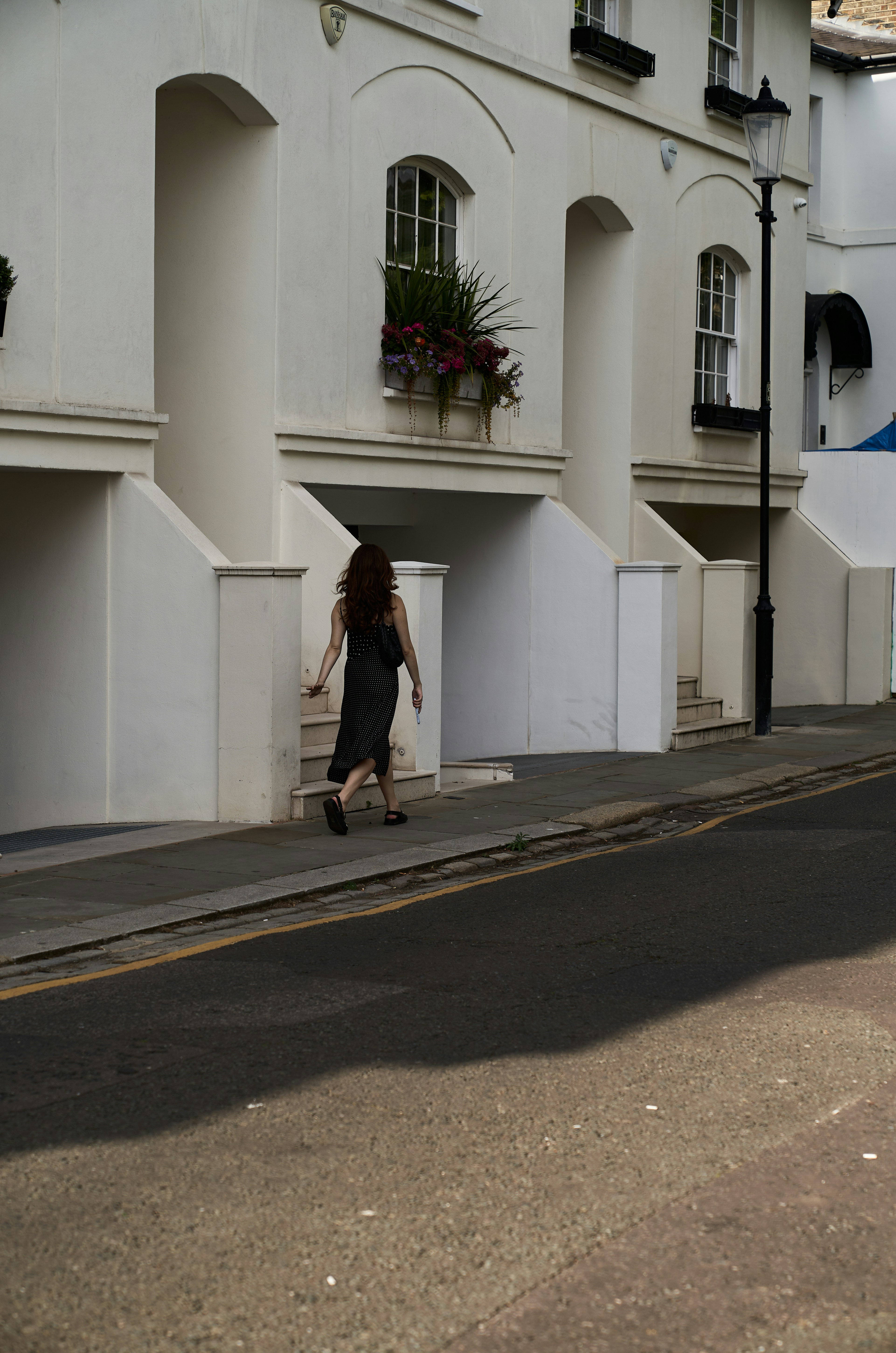 Eine Frau, die eine Straße neben einem hohen weißen Gebäude entlanggeht