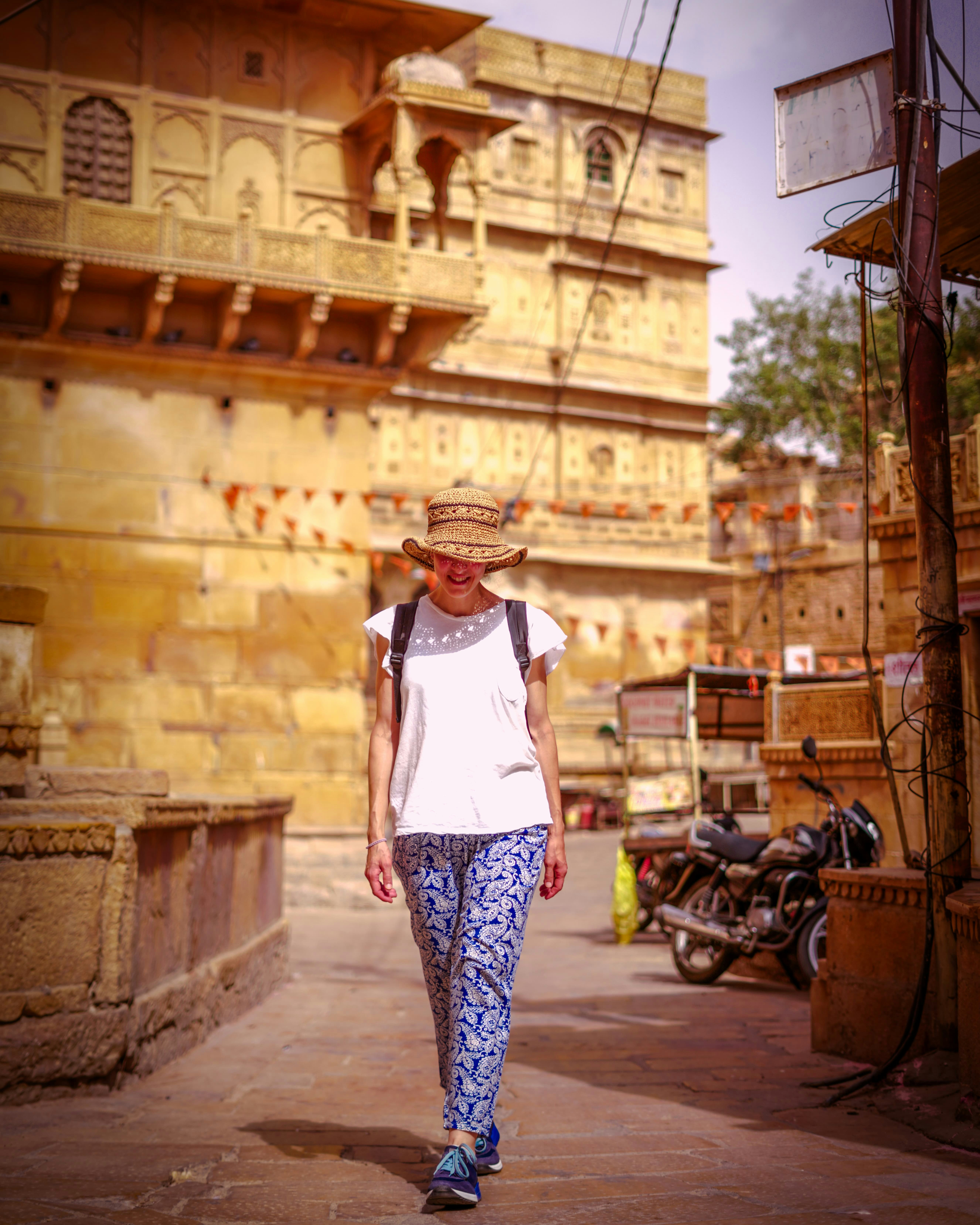 A woman walking down a street next to a tall building