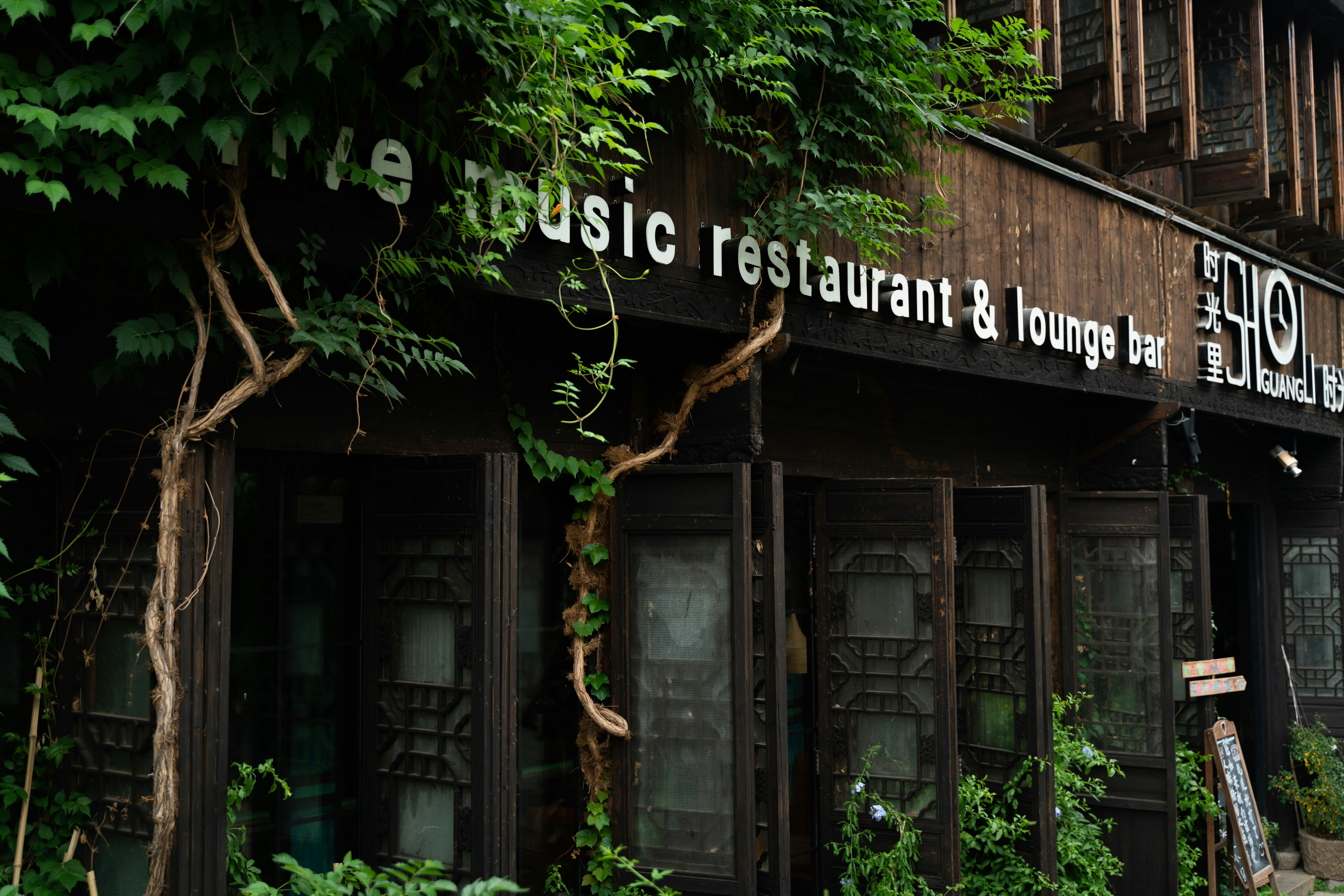 The outside of a restaurant with lots of plants growing on it
