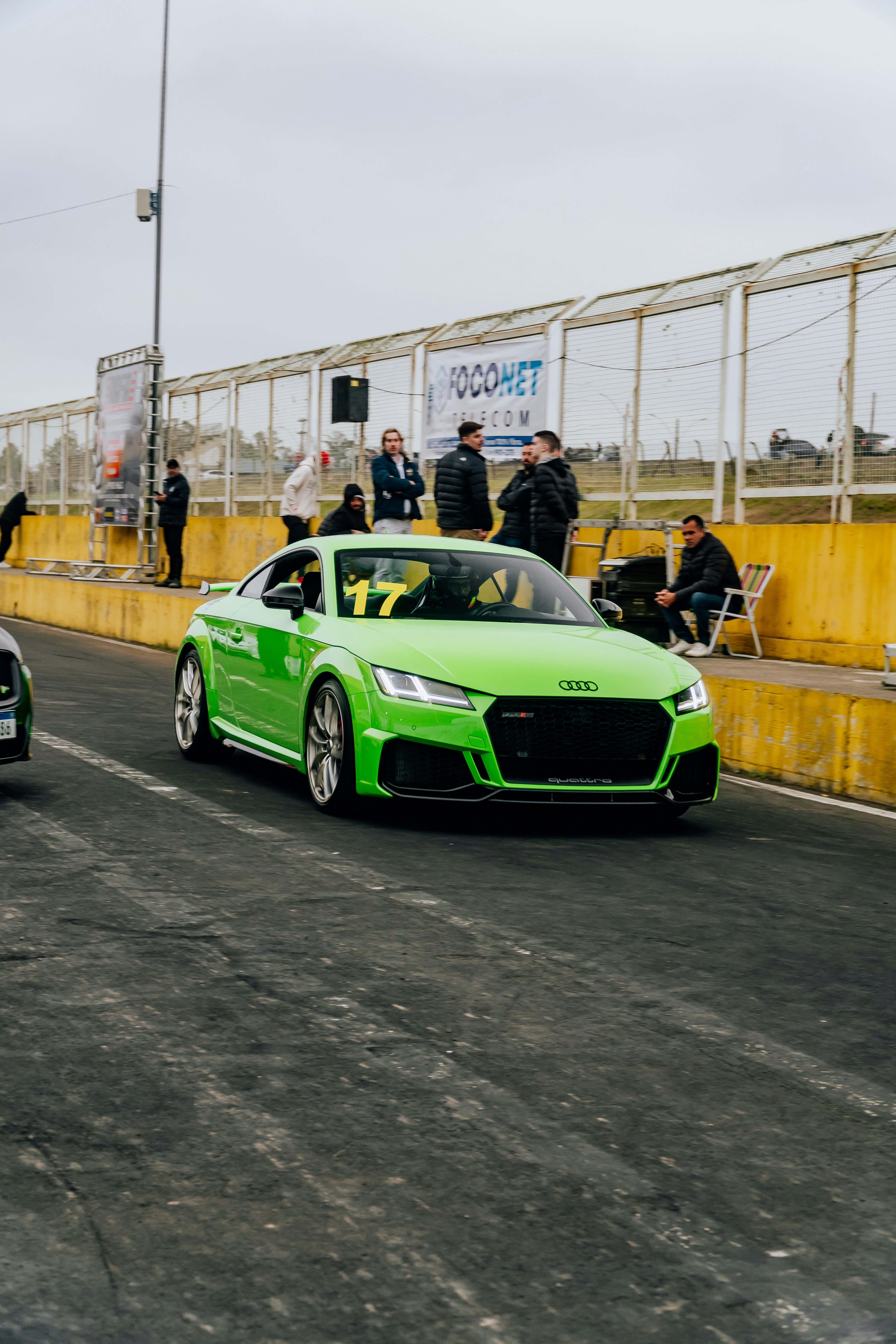 A couple of green cars driving down a street