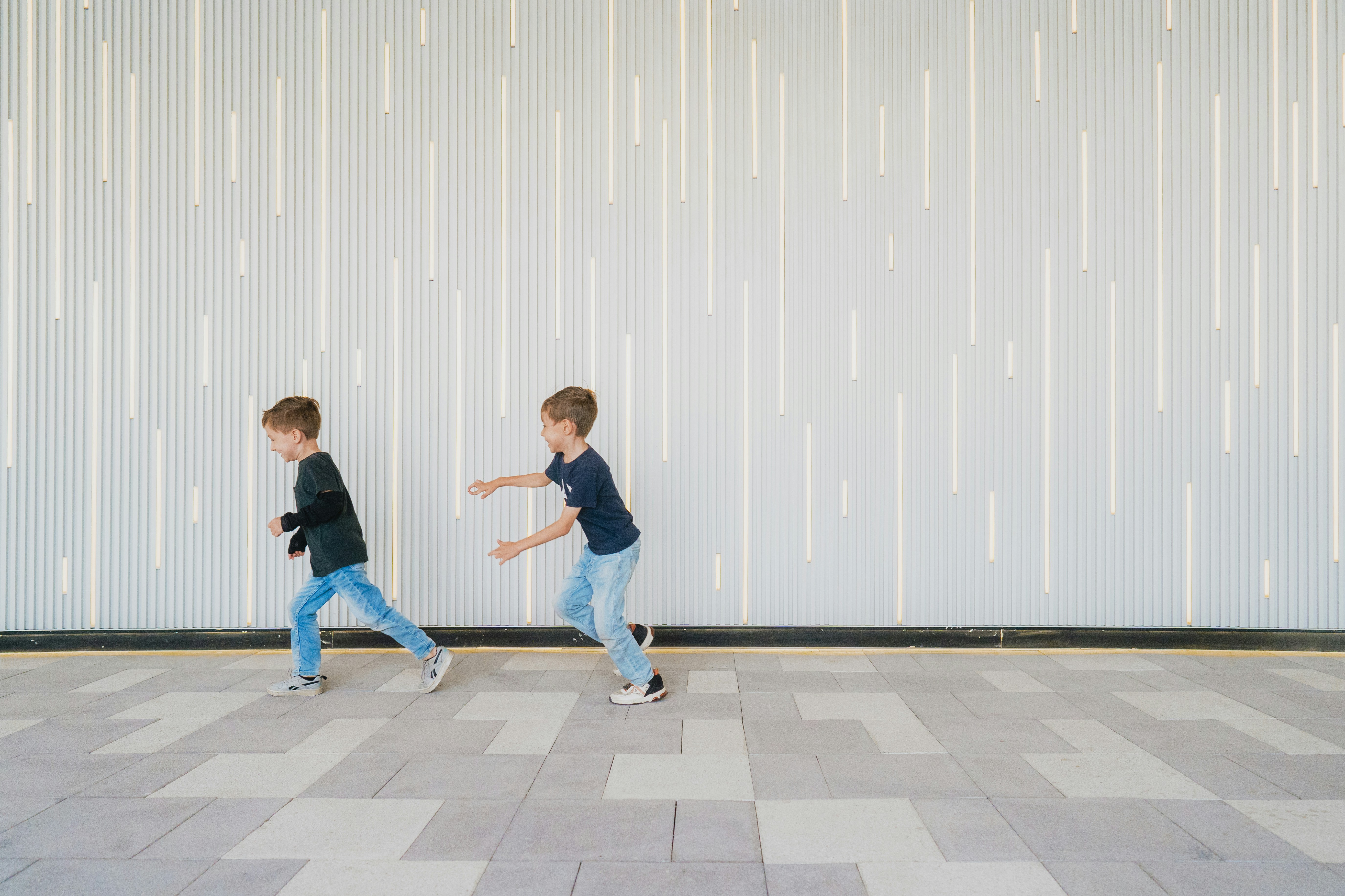 Two young boys are running on a checkered floor