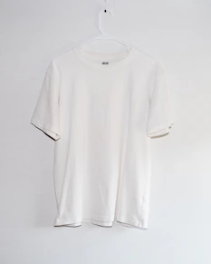 A white t - shirt hanging on a white wall