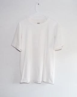 A white t - shirt hanging on a white wall