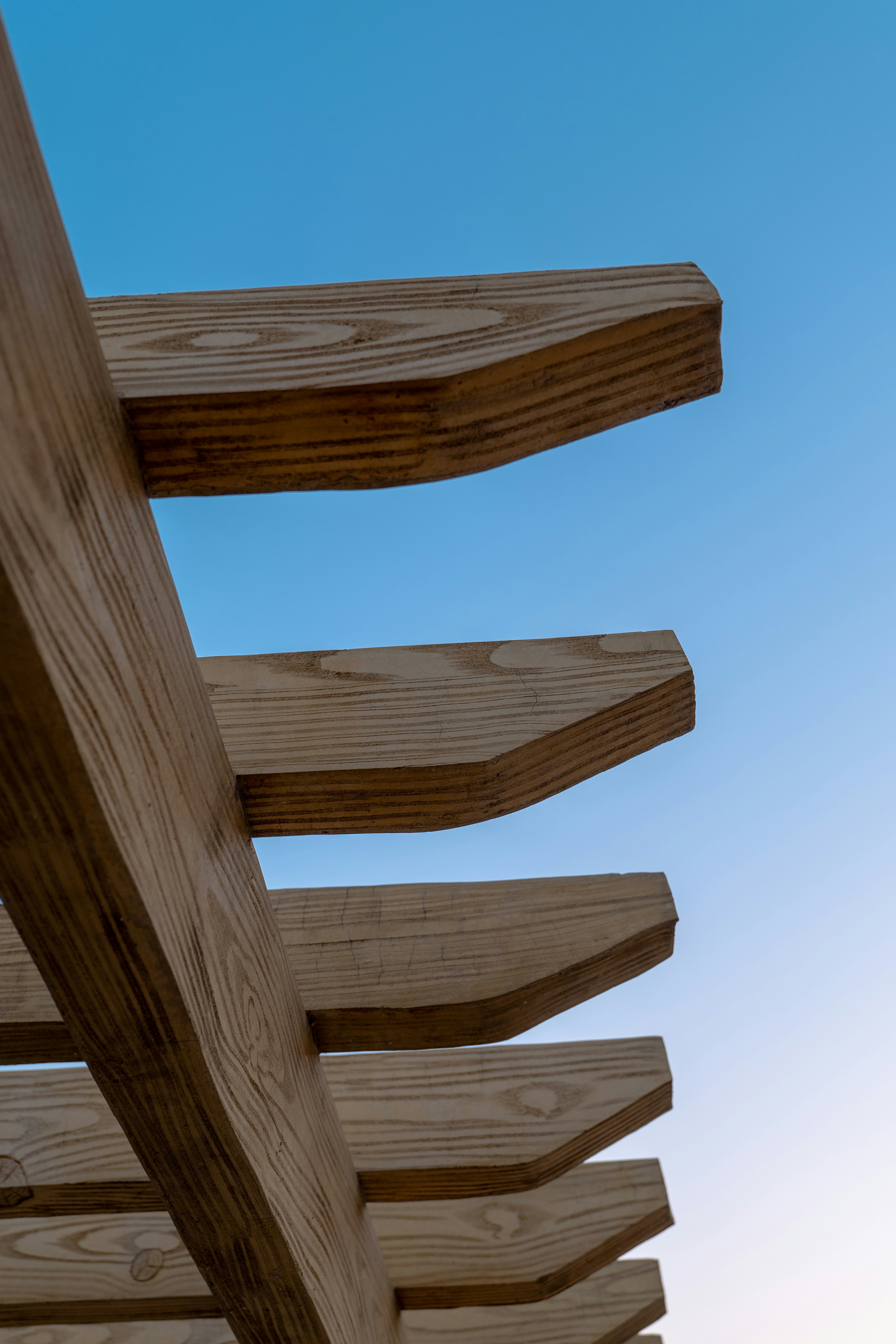 A close up of a wooden bench against a blue sky
