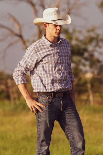 A man standing in a field wearing a cowboy hat