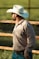 A man wearing a cowboy hat standing in front of a fence